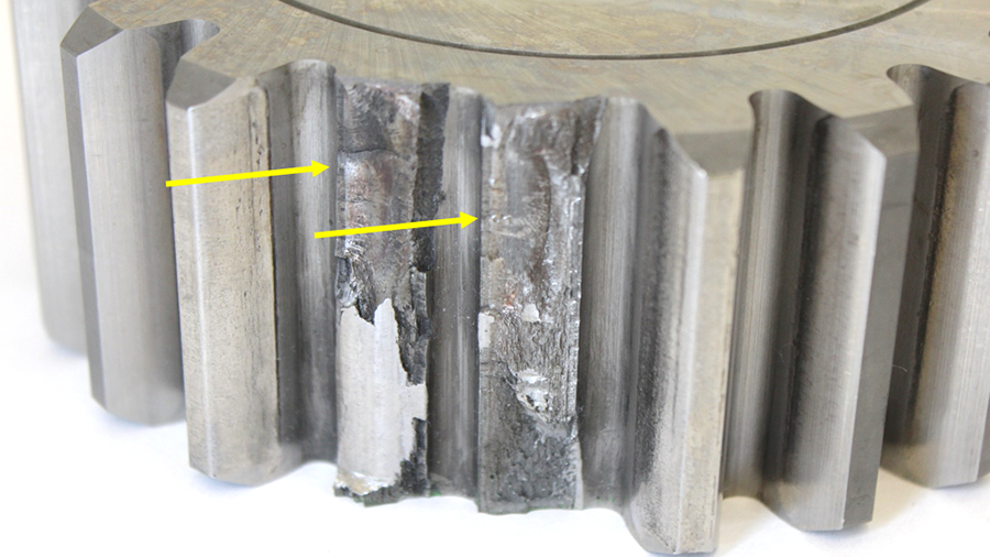Close-up view of gear pitting damage caused by fatigue and lubrication failure on metal gear teeth.