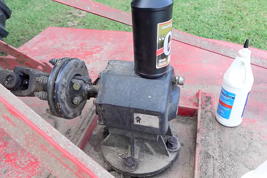 The picture shows a gearbox that is leaking oil, with several bottles of lubricant placed nearby.