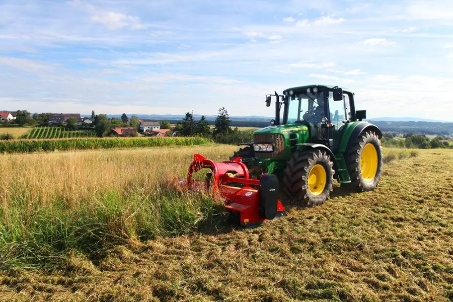 Tractor working with flail mower in agricultural field